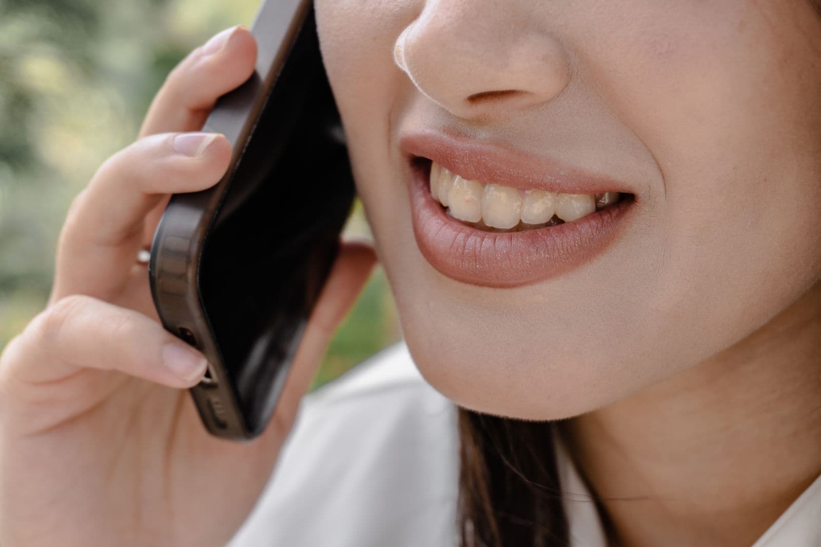 Close crop of someone smiling while holding a phone to their ear.